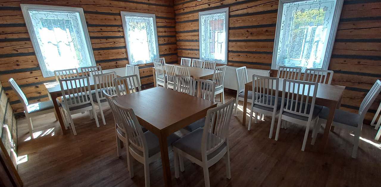 Jídelna chalupy Anička s dlouhým stolem a roubenými stěnami